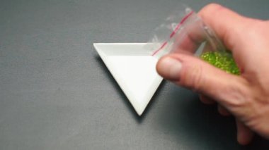 Yeşil boncukları üçgen bir plakaya döküyorum.