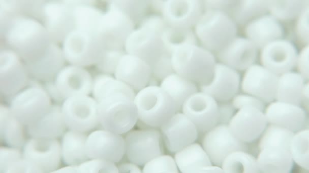 Weiße Schmuckperlen liegen auf einem weißen Teller in einer Schmuckwerkstatt — Stockvideo