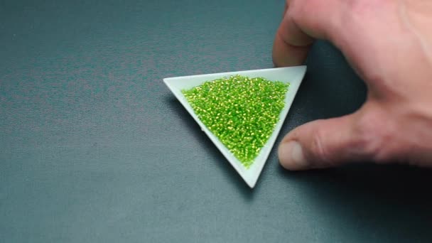 Detailní záběr na ruku točí trojúhelníkový talíř se zelenými korálky. — Stock video