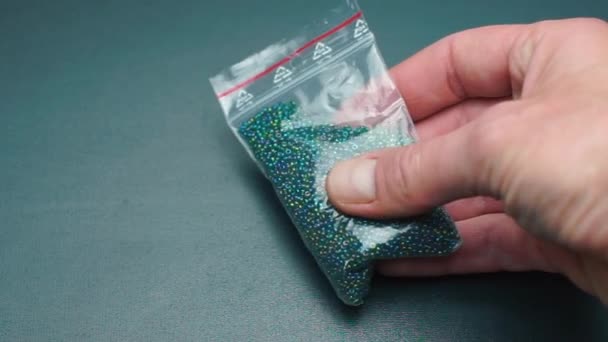 Le vendeur tient un sac avec des perles de bijoux . — Video