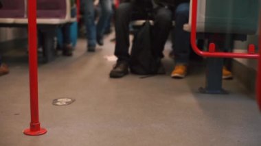 Tren vagonunda yürüyen bir yolcunun ayakları. Yolcu bir yer seçer..