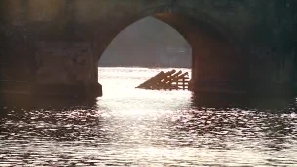 O arco da ponte velha no rio. O sol reflete na água . — Vídeo de Stock