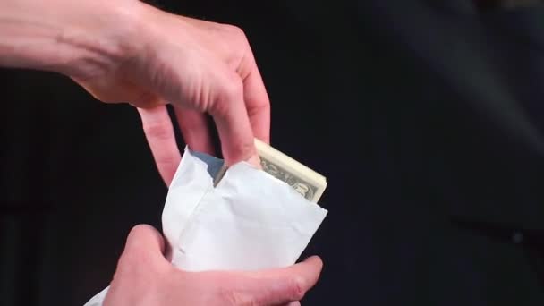 Человек прячется и достает пачку стодолларовых купюр из белой сумки. . — стоковое видео