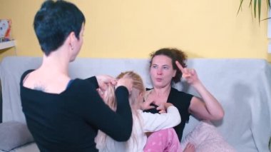 Evdeki kanepede iki anne lezbiyen. Annenin kucağı bir kızdır..