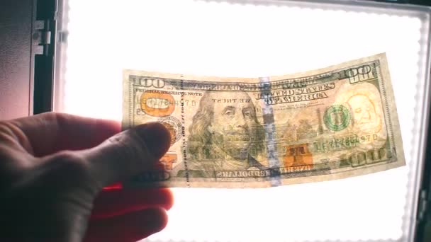 Demostración de un billete real de cien dólares en luz brillante . — Vídeo de stock