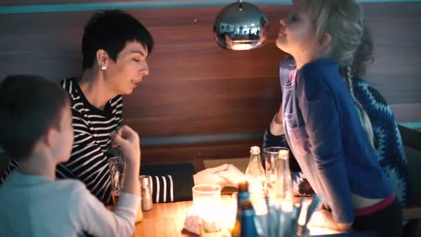 Twee lesbiennes met kinderen aan tafel in een restaurant. — Stockvideo