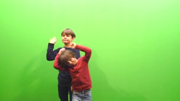 Dois meninos estão dançando em um fundo verde — Vídeo de Stock