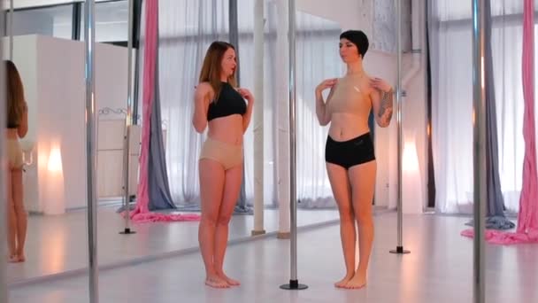 Dwie dziewczyny wykonują ćwiczenia taneczne na słupie. — Wideo stockowe