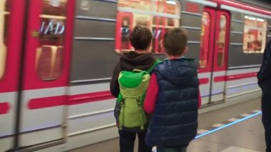 Üç çocuk metroda treni bekliyor.
