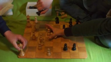 Çocukların elleri satranç taşlarını bir kutuya koyar.