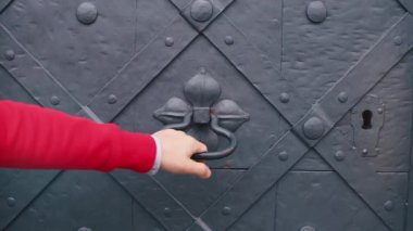 Bir adam özel saplı eski bir kapıyı çalar.