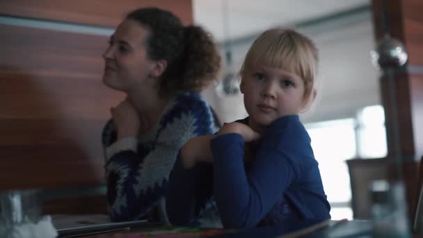 Mamá y su hija están sentadas en una mesa en un restaurante . — Vídeos de Stock