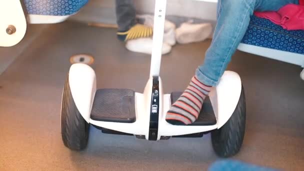 Een jongen zit in een treinstoel. Benen houdt een gyroscooter. — Stockvideo