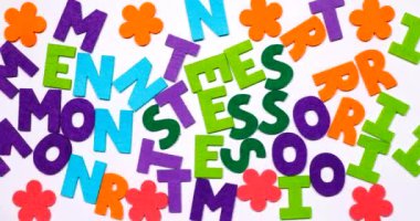 Montessori kelimesi. Kelime renkli bir yazı tipiyle dans harfleriyle yazılmış.