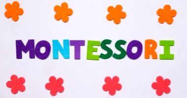 Montessori kelimesi. Kelime renkli bir yazı tipiyle dans harfleriyle yazılmış..