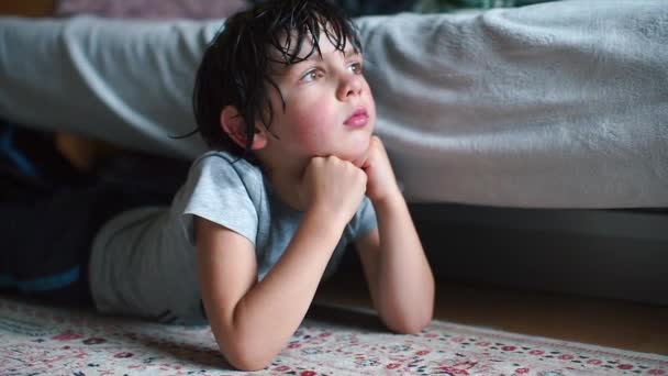 Il bambino con i capelli bagnati si trova sul pavimento nella stanza, la sua testa giace sulle mani — Video Stock