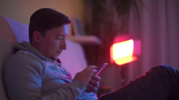 De man in de nachtclub houdt een smartphone vast — Stockvideo