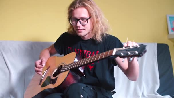 Der Typ stimmt eine Akustikgitarre auf gelbem Hintergrund. — Stockvideo