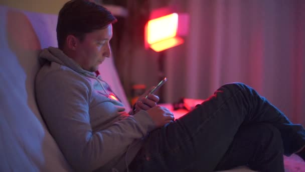 Een man op een feest schrijft een bericht op een smartphone naar een meisje — Stockvideo