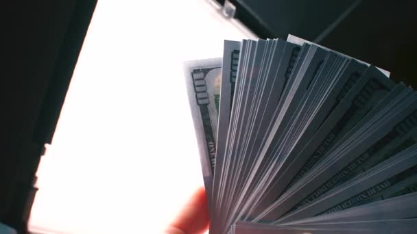 Parlak ışığın arka planına karşı 100 dolarlık banknotlar. — Stok video