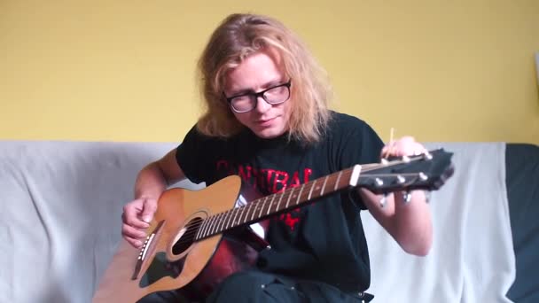 Een man met lang haar speelt een akoestische gitaar — Stockvideo