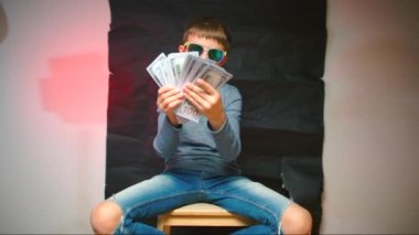 Çocuk elinde bir sürü para gösteriyor..