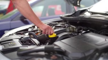 Araba sürücüsü motor yağı kapağını açar