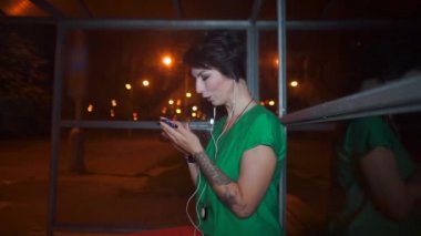 Fahişe, toplu taşıma durağında akıllı telefon kullanıyor.