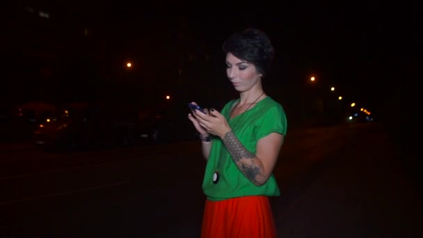 Yeşil bluzlu ve kırmızı etekli kız akıllı telefon ekranına bakıyor. — Stok video