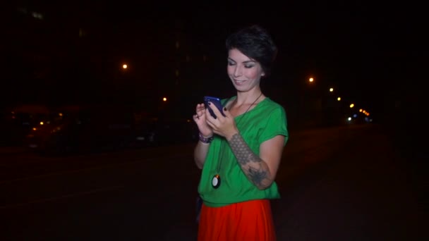 Смартфон в руках дівчини, яка стоїть біля дороги, чекаючи таксі — стокове відео