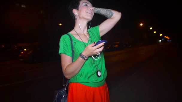 Ragazza in abiti luminosi utilizza uno smartphone di notte — Video Stock