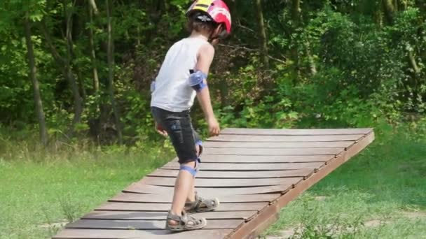 Um menino em um capacete encontra-se em um balanço — Vídeo de Stock