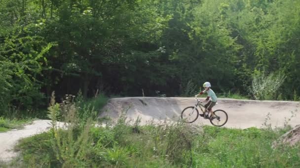 School of cyclists, a boy rides on artificial mountains — ストック動画