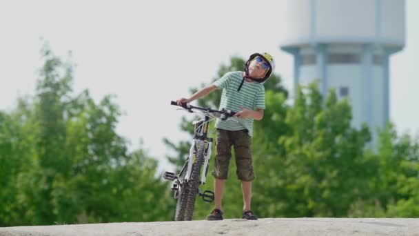 O menino segura uma bicicleta de montanha em suas mãos, começa a se mover com uma bicicleta — Vídeo de Stock