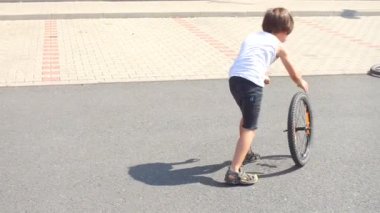 İki adam evin avlusunda bisikletin tekerlekleriyle oynuyorlar.