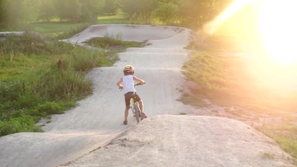 Een jongen met een helm begint te fietsen langs de baan in wedstrijden — Stockvideo