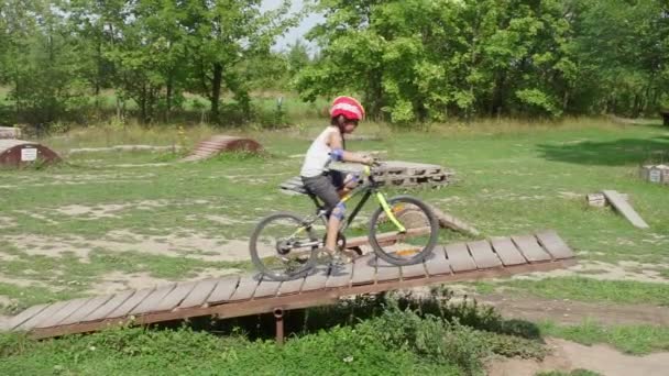 Niño monta una bicicleta de montaña en un parque de conducción de bicicletas extremo — Vídeos de Stock