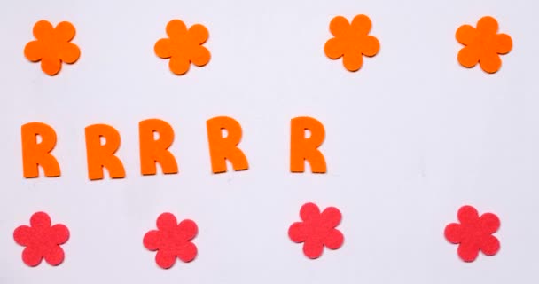 The orange letter R flies from side to side. Top and bottom flowers are moving. — Stock Video