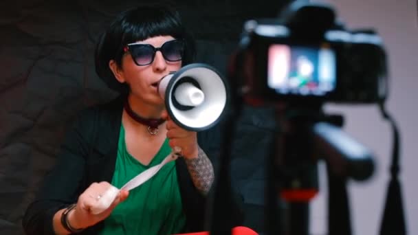 En flicka med en megafon i händerna spelar in en vädjan till en videokamera. — Stockvideo