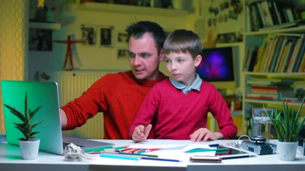 A father explains financial knowledge to his son at a table in the office. — Stock Video