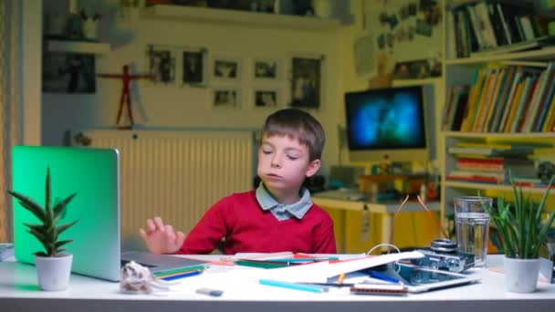 Хлопчик за столом робить шкільну роботу . — стокове відео
