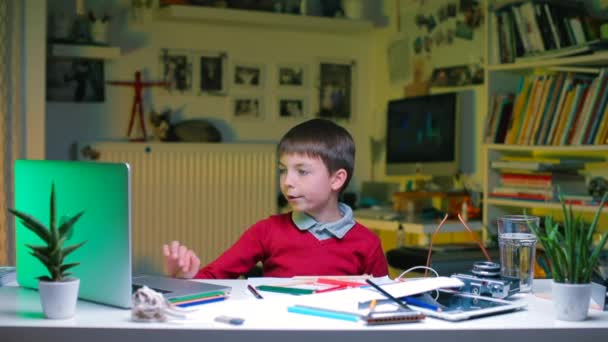 Дитина за столом виконує завдання, жує їжу . — стокове відео