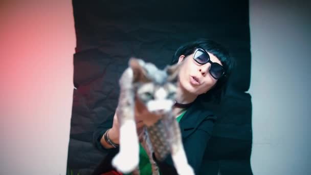 Ένας μπλόγκερ με μαύρα γυαλιά κρατά μια γάτα στα χέρια του. — Αρχείο Βίντεο