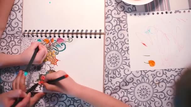 Les écoliers à la table dessinent une image en couleur sur papier . — Video