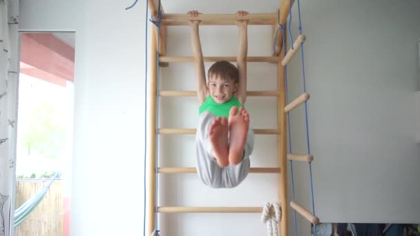 Retrato de un niño haciendo ejercicio sobre los músculos abdominales en la barra horizontal — Vídeo de stock