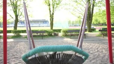 Çocuk bir spor stadyumunda salıncakta sallanıyor.