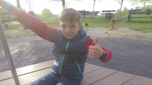 Мальчик ездит на карусели и показывает, как — стоковое видео