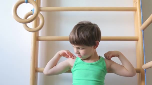 Child shows biceps on the playground at school — ストック動画