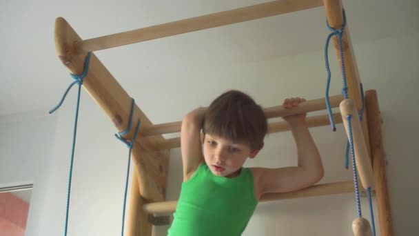 El niño se está preparando para hacer un ejercicio deportivo en la barra horizontal — Vídeo de stock