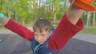 Çocuk atlıkarıncaya biniyor, korkuluklara tutunuyor.